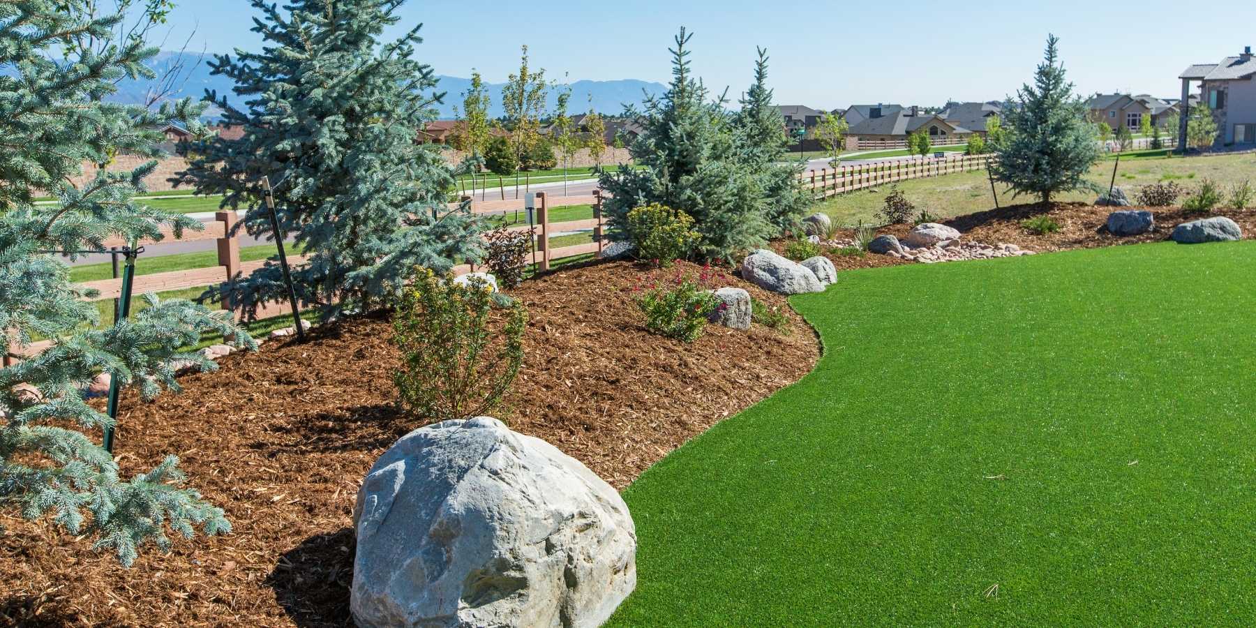 Artificial grass lawn installed in a landscape with mulch